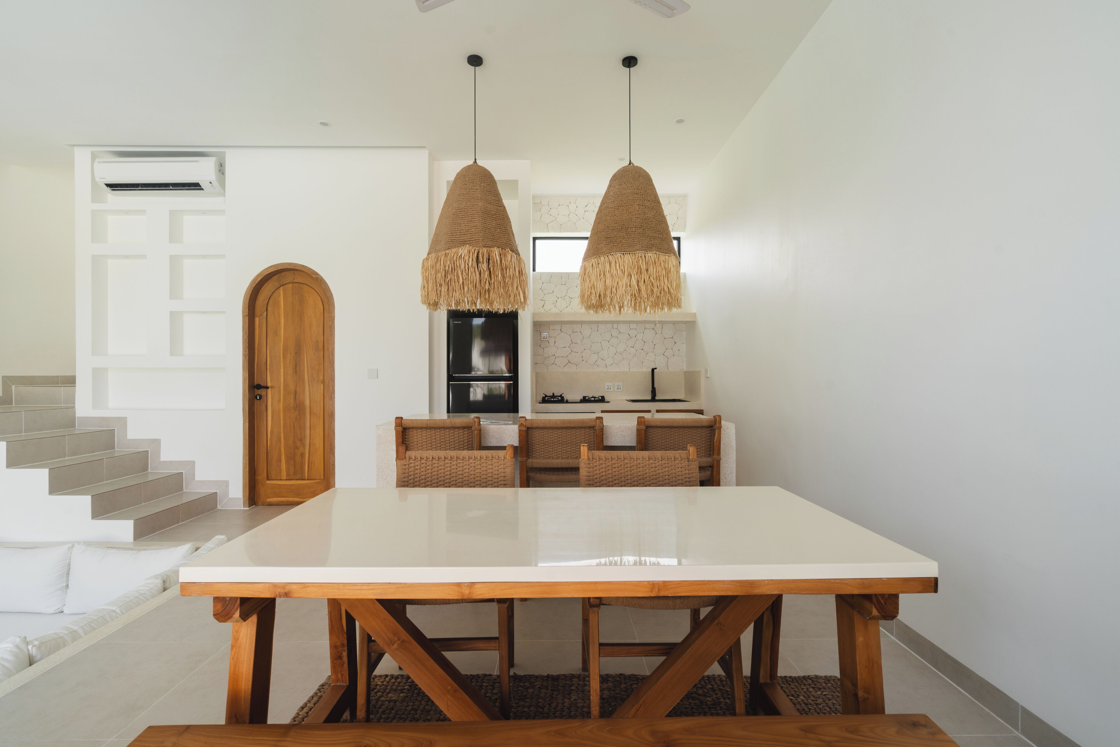 A modern kitchen with a white countertop, two hanging pendant lights, and a built-in oven.
