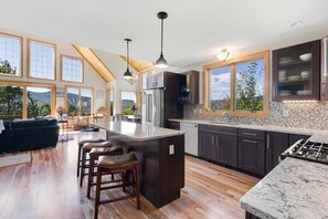 A spacious kitchen with a large island, dark cabinetry, and a view of the outdoors. - Outlook at The Peaks (Newry)
