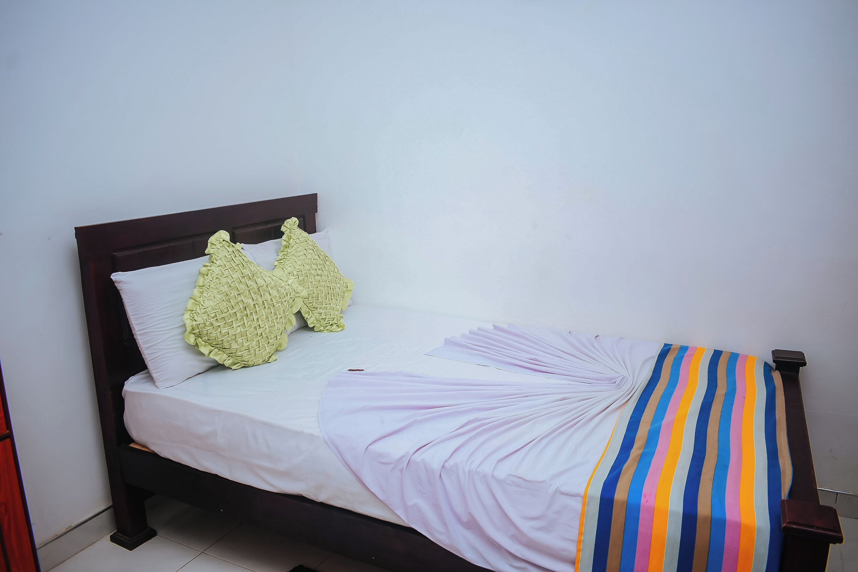 Un lit avec un drap blanc, deux oreillers et une couverture à rayures.