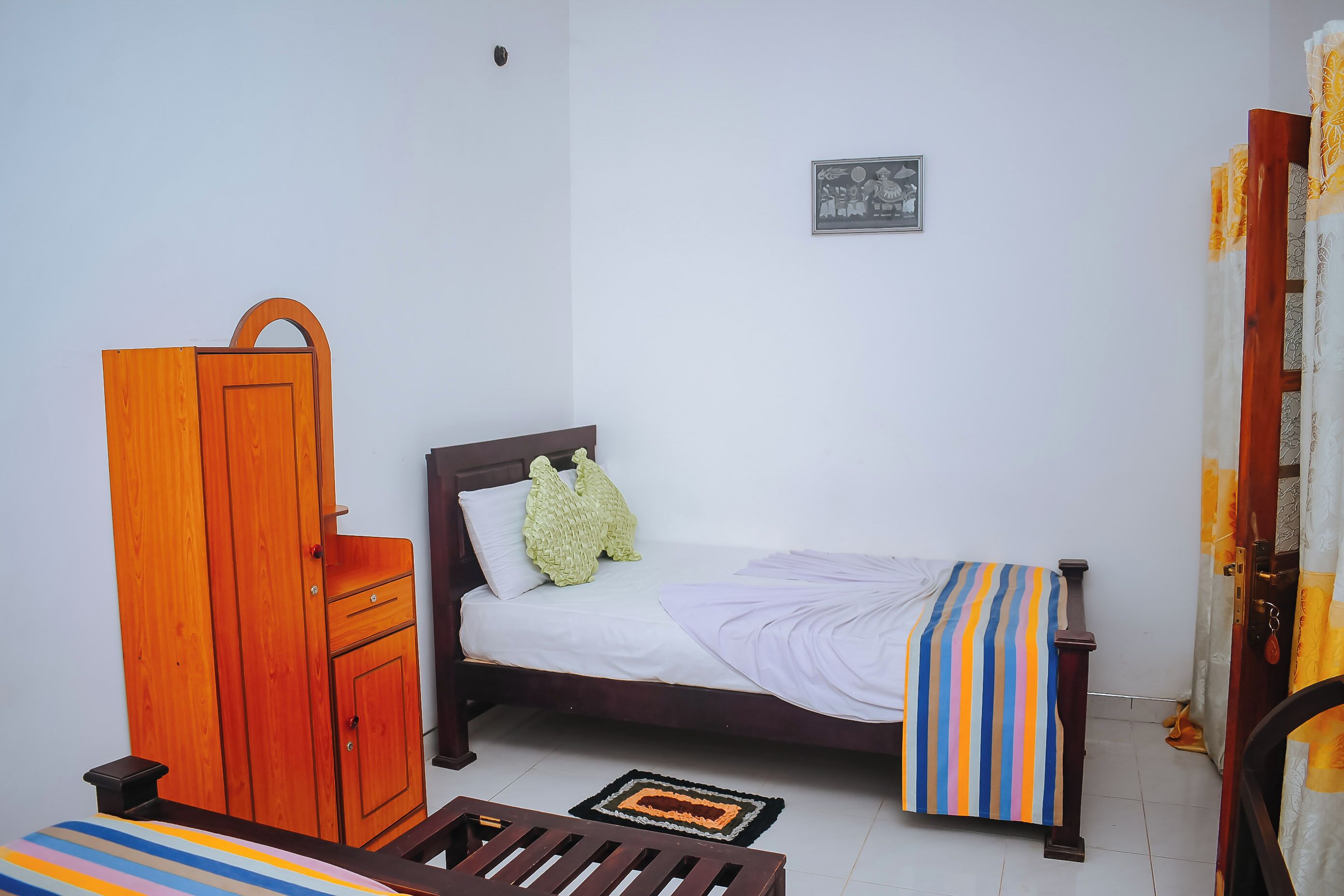 Una habitación pequeña y sencilla con una cama, un armario de madera y una mesita.