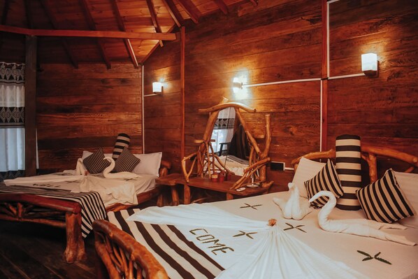 A wooden cabin room with two beds, each with striped bedding and swan-shaped pillows. - Dudley Nature Resort  (Habarana)