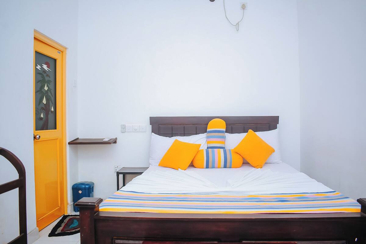 Un dormitorio con cama, mesita de noche, estante en la pared, puerta y decoración mural.