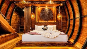 A wooden interior with a bed, a decorative wall, and a hanging light fixture. - Dudley Nature Resort  (Habarana)