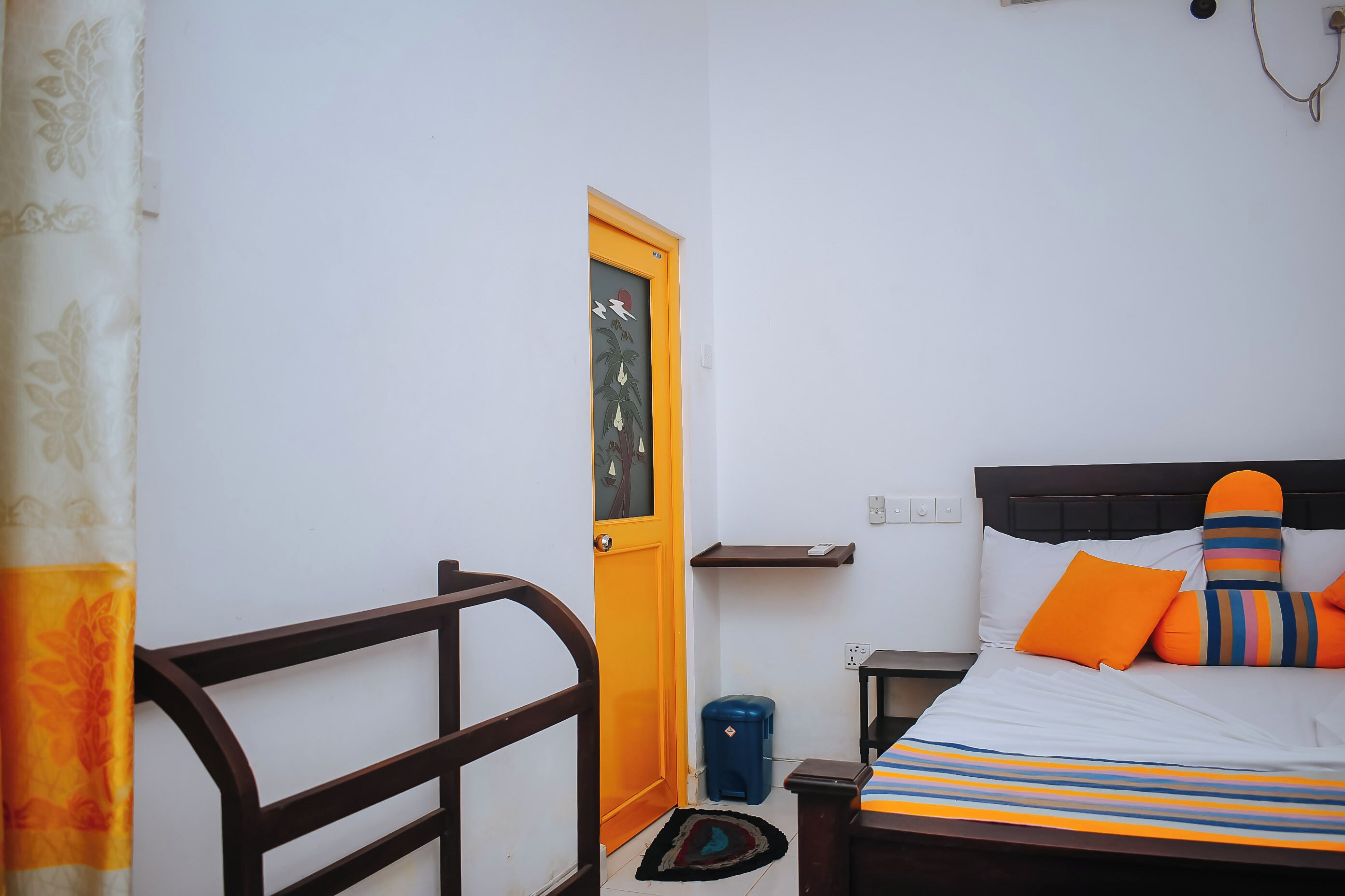 A bedroom with a bed, a nightstand, a small table, a chair, a door, and a window.