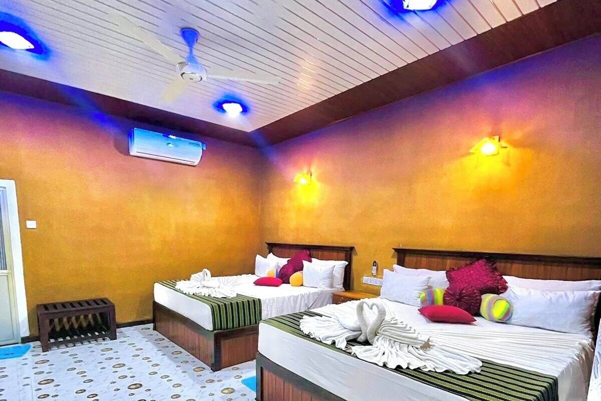 Una habitación de hotel con dos camas, ventilador de techo y aire acondicionado.