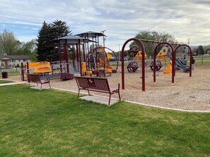 A playground with swings, slides, and a covered seating area.