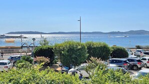 A parking lot with cars, a flagpole, and a view of the sea.