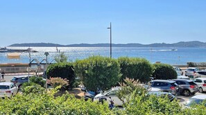 A parking lot with cars, a flagpole, and a view of the sea. - Apartment T2 - 4 people - City center and beach - Sea view - Air conditioning - WiFi - Sainte-Maxime (STE MAXIME)