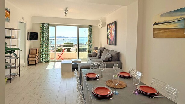 A dining area with a table set for four, a sofa, and a view of the sea.