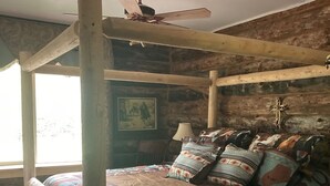 A rustic wooden four-poster bed with a ceiling fan, a patterned bedspread, and multiple pillows. - Bear Creek Hideaway Log Cabin on River Fishing & WiFi on Kebler Pass (Somerset)