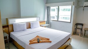 Hotellihuone, jossa on suuri sänky, pieni pöytä, tuoli ja ikkuna, josta on näkymä rakennuksiin.