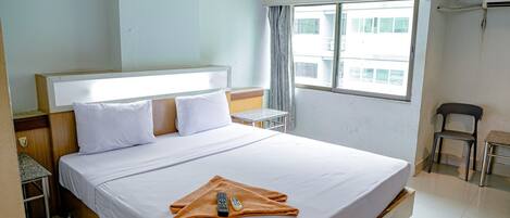 Habitación de hotel con una cama grande, una mesita, una silla y una ventana con vistas a edificios.