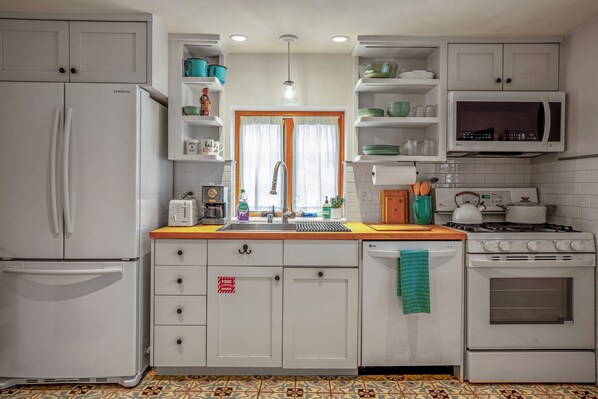 A kitchen with white cabinets, a Samsung refrigerator, a microwave, an LG dishwasher, and a stove.