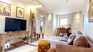 Ein modernes Wohnzimmer mit Flachbildfernseher, einer Couch, einem Couchtisch und einem Essbereich mit Tisch und Stühlen.