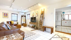 Ein modernes Wohnzimmer mit einem braunen Ledersofa, einem Fernseher und einem Bild an der Wand.