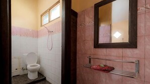 Et badeværelse med toilet, bruser, spejl og et håndklædetørrestativ.