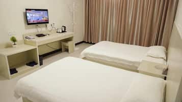 A hotel room with two beds, a desk with a TV, a coat rack, and a window with curtains.