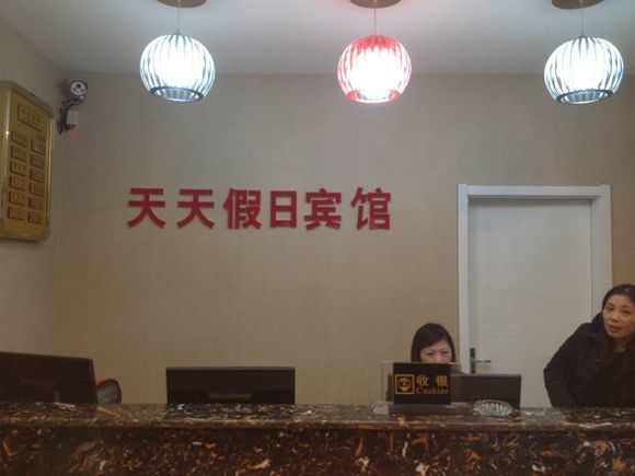 A reception desk with a sign, two computers, and a door in the background.