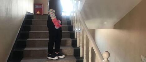 A person standing on a staircase with a handrail on the right.