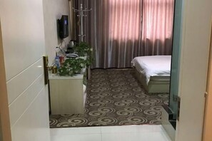 A hotel room with a bed, a small bedside table, a TV, and a curtain. - Civil rights Holiday Inn (Minquan)