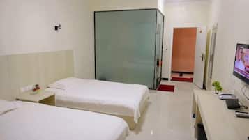 A hotel room with two beds, a desk with a computer, a TV, and a sliding door leading to a bathroom.