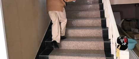 A person descending a staircase with a handrail on the right.