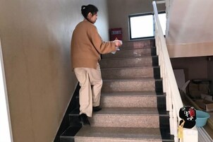 Una persona bajando una escalera con barandilla a la derecha.