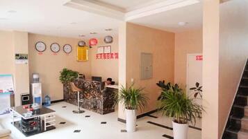 A reception area with a reception desk, a water dispenser, a clock, and a sign indicating the hotel name.