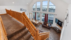 Ein geräumiger Wohnbereich mit einer Holztreppe, einem Esstisch und einem großen Fenster mit Blick nach draußen.
