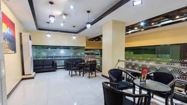 A modern restaurant with a clean, tiled floor and a mix of black and wooden furniture. There are multiple tables and chairs, and a decorative wall with a fan-like pattern. - Hotel Sogo Cainta (Cainta)