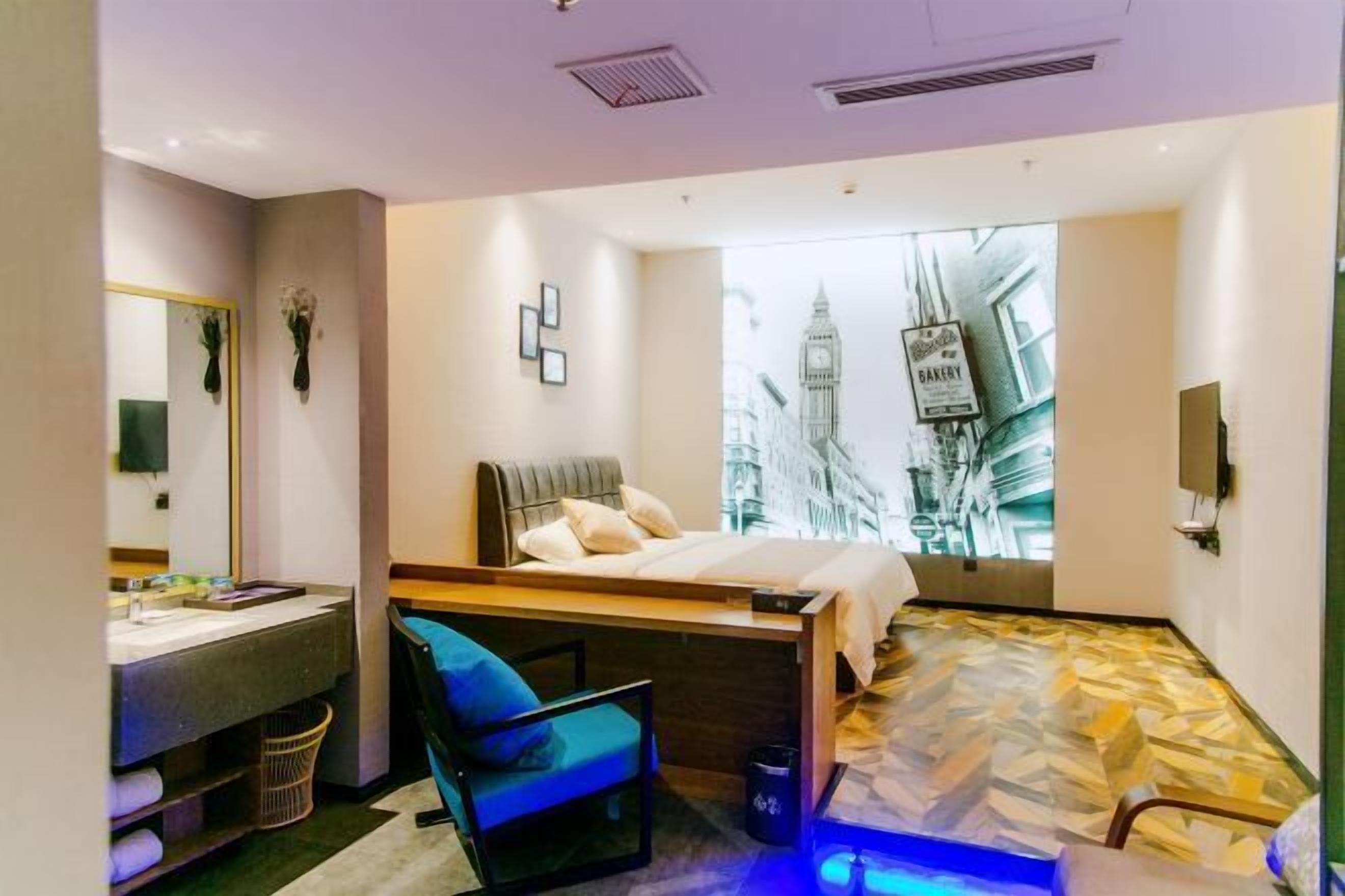 Ein modernes Hotelzimmer mit einem Bett, einem Schreibtisch, einem Sessel und einem großen Fenster mit Blick auf die Stadt.