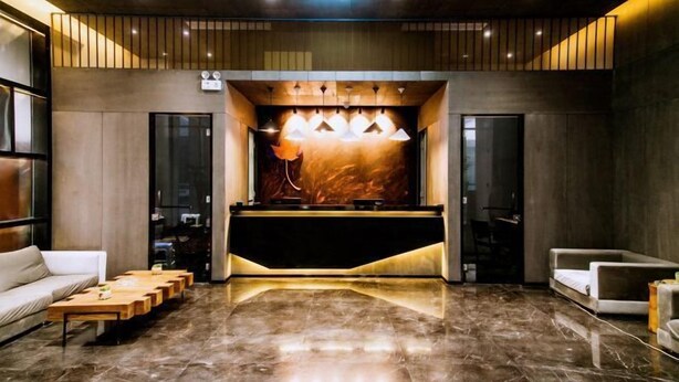 A modern lobby with a reception desk, seating area, and a large mirror. - Wuxi Fengshe Boutique Hotel (Jiangnan University Taihu Scenery Belt Store) (Wuxi)