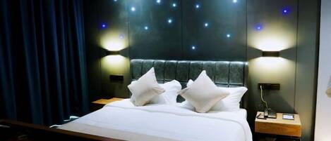 A modern hotel room with a large bed, two bedside tables, and a wall with illuminated star-like lights.