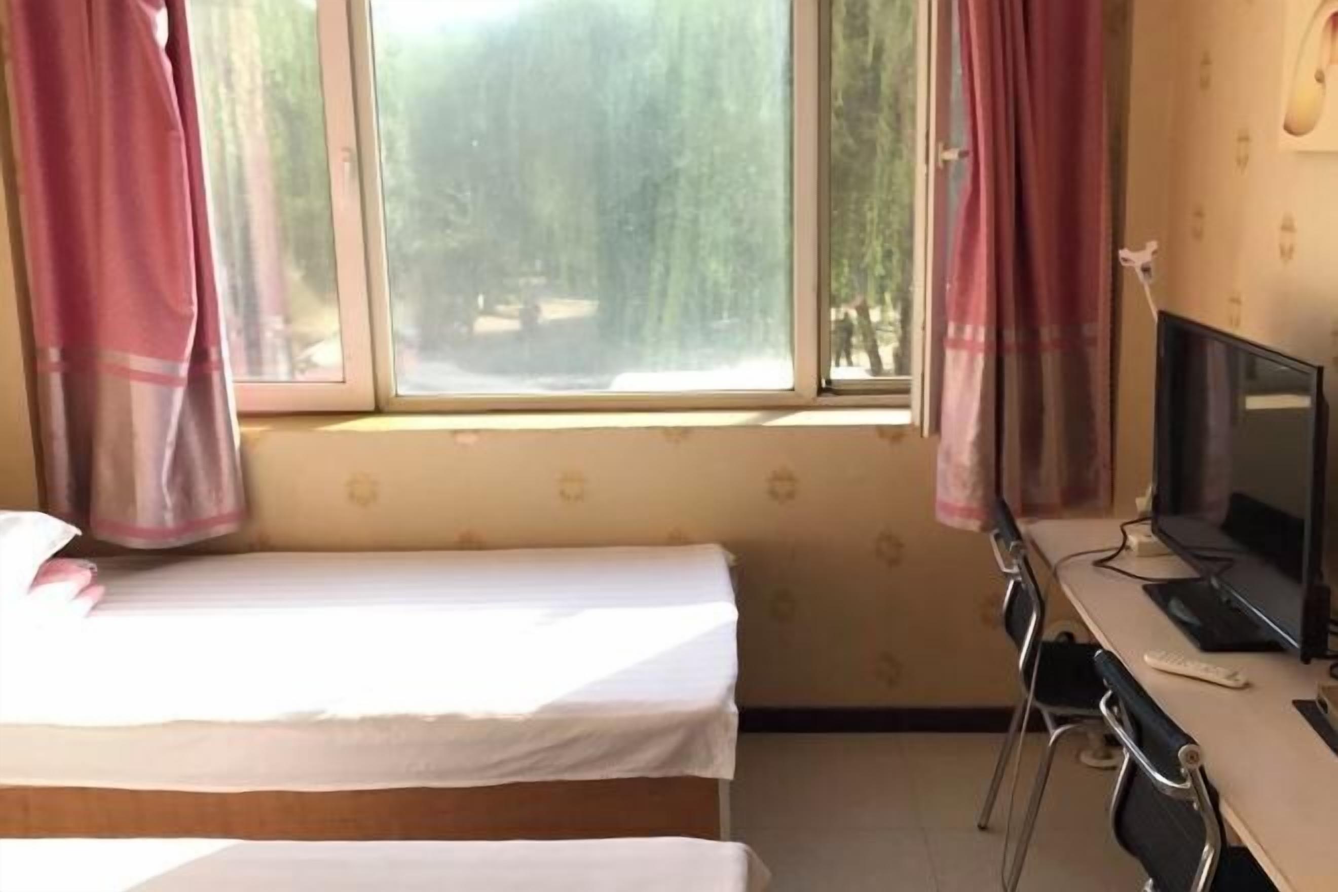 A room with a bed, a desk with a computer, and a window with curtains.