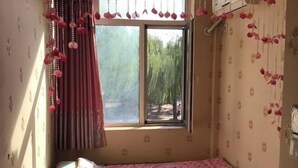 A small room with a single bed, a window with curtains, and a wall-mounted air conditioning unit. - Hengchang Hotel (Shenyang)