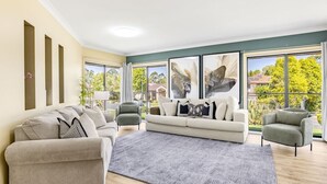 Ein modernes Wohnzimmer mit einem beigen Sofa, einem grauen Sessel und einem gemusterten Teppich.