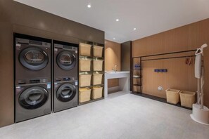 A laundry room with four wall-mounted washing machines, a sink, and a drying rack.