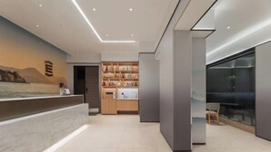 A modern reception area with a marble counter, a bookshelf, and a large window with a city view. - Yilong Anyun Hotel (Rudong Chahe Middle School) (Rudong)