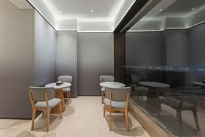 Un intérieur moderne avec des tables et des chaises rondes, une cloison en verre et un éclairage encastré au plafond.