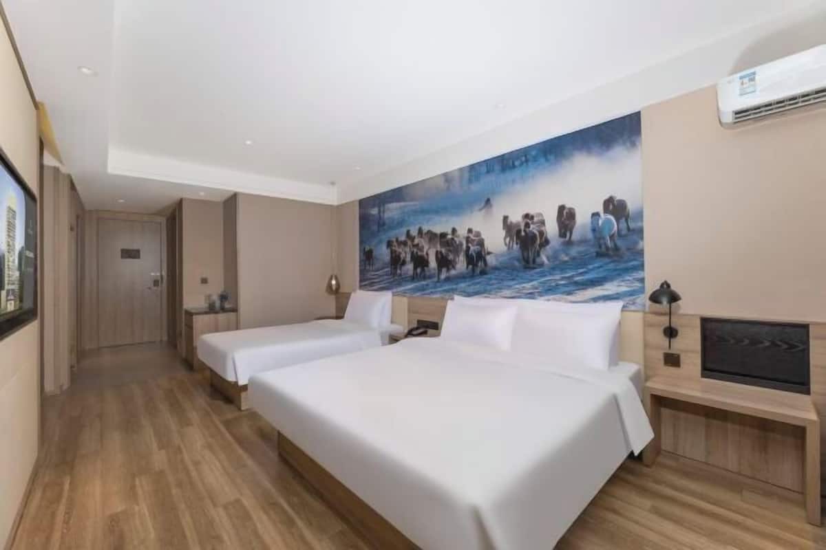 A hotel room with two beds, a large painting on the wall, a TV, and a wooden floor.