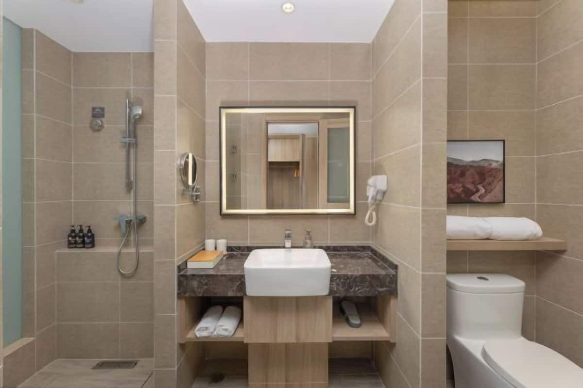 A modern bathroom with a shower, toilet, sink, and a large mirror.