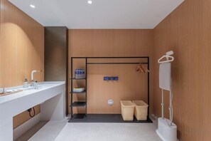A modern bathroom with a white sink, shelves, a towel rack, and a shower area. - Yilong Anyun Hotel (Rudong Chahe Middle School) (Rudong)