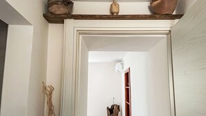 A hallway with a wooden shelf holding decorative items, a wooden floor, and a white door leading to another room. - delle Maschere by Interhome (Valli del Natisone)