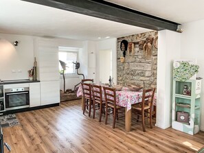 Eine moderne Küche mit Essbereich, Holzboden und einer Steinwand mit Masken.