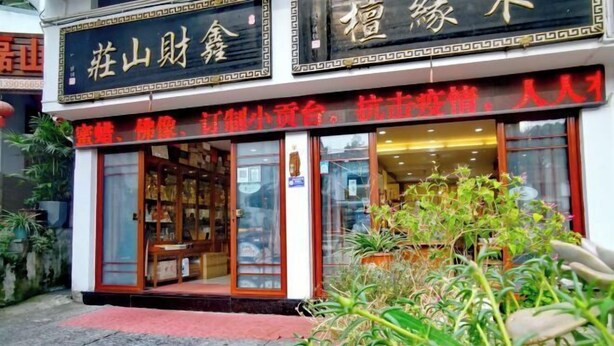 Ein Schaufenster mit traditioneller chinesischer Architektur, einschließlich einer Holztür und Glasfenstern.