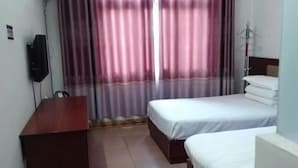 Habitación de hotel con dos camas, un escritorio de madera, un televisor y un armario.