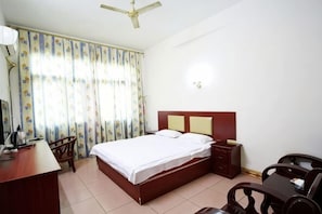 Une chambre d’hôtel équipée d’un lit, d’un bureau, d’une chaise et d’un ventilateur de plafond.
