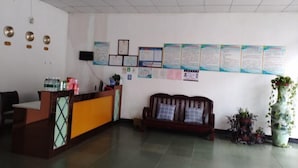 Un área de recepción con mostrador, un sofá y varios carteles informativos en la pared.