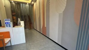 Ein Hotel-Empfangsbereich mit modernem Design, inklusive einer Rezeption, einer Sitzecke und einem Korridor zu anderen Bereichen des Hotels.