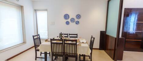Un comedor con una mesa dispuesta para cuatro personas, rodeada de sillas y una pared decorativa con platos azules.